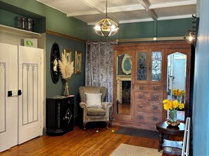 A room with a wooden floor, a chair, a cabinet, a mirror, and a door with glass panels. - Humphreston House (Bristol)