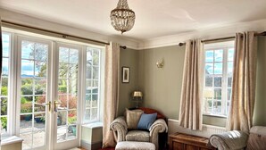 Ein Zimmer mit großem Fenster, einer Chandelier, einem Sofa und einem Holzschrank.