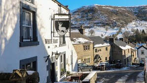 A white building with a sign reading "White Hart" and a deer emblem. - Peak Cottage (Hope Valley)