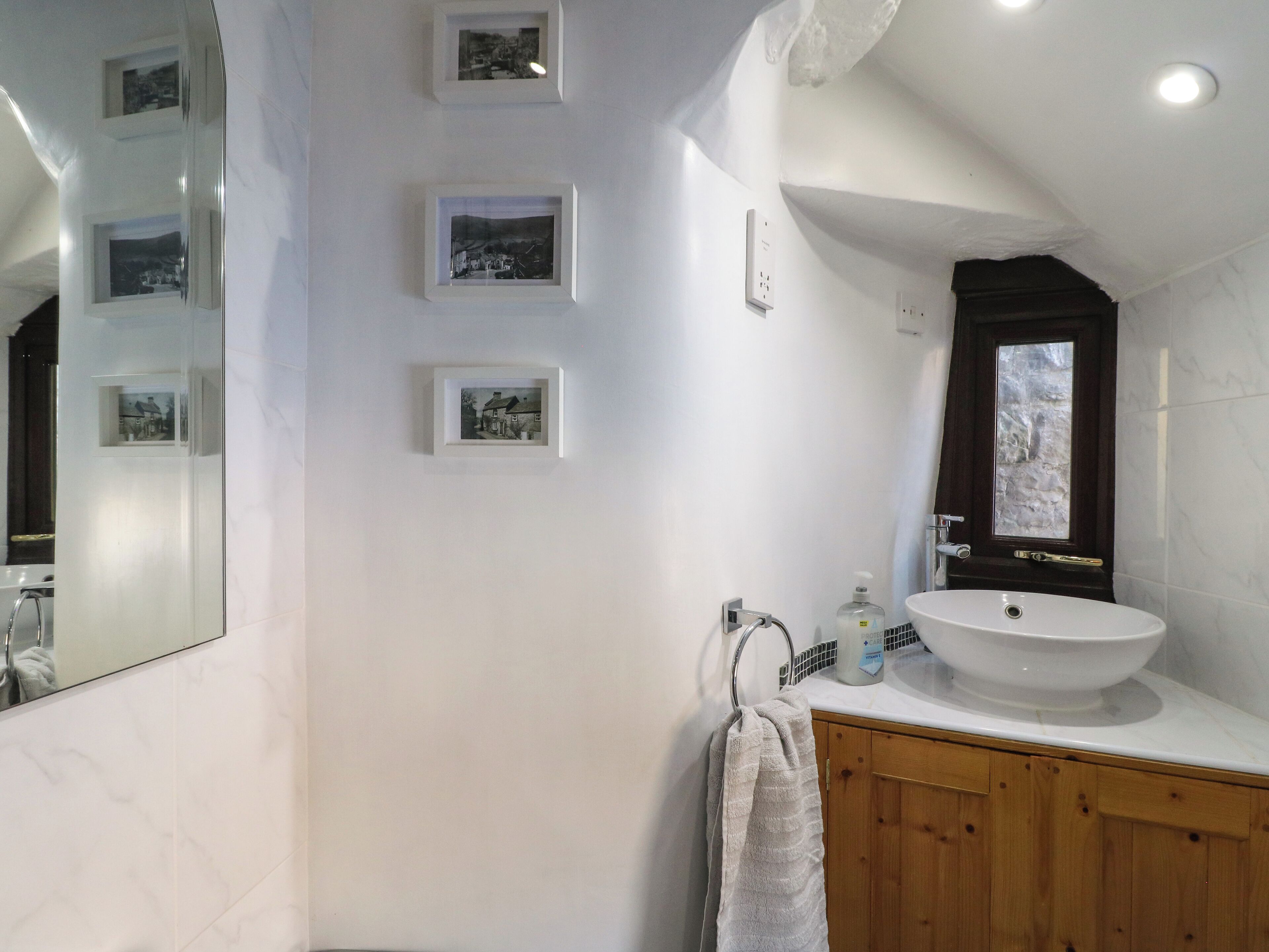 Ein Badezimmer mit einem großen Spiegel, einer Holzanrichte, einem Waschbecken und gerahmten Bildern an der Wand.