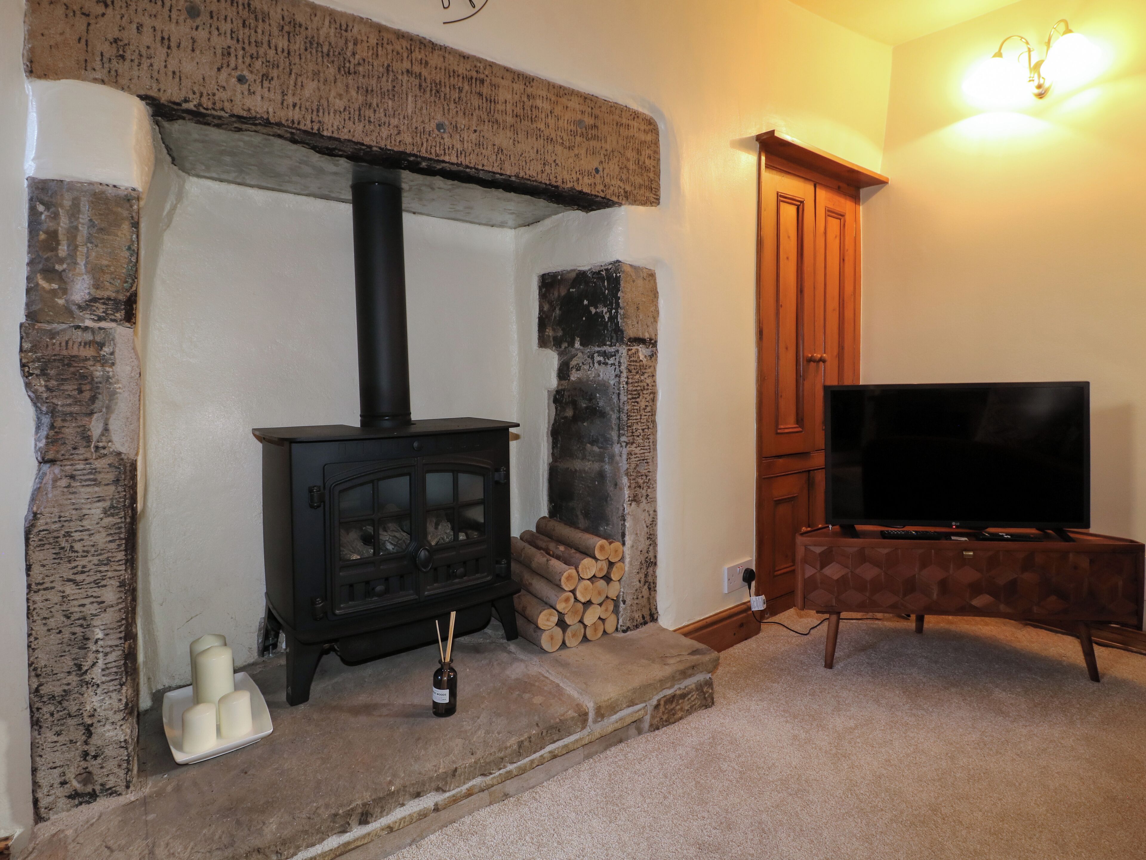 A cozy living room with a wood-burning stove, a television, and a fireplace.