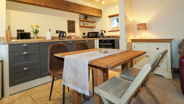 A modern kitchen with a wooden table, two chairs, and a bench. - Peak Cottage (Hope Valley)