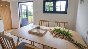 A dining area with a wooden table, chairs, a vase of flowers, and a window with a view of greenery. - The View (Wrexham)