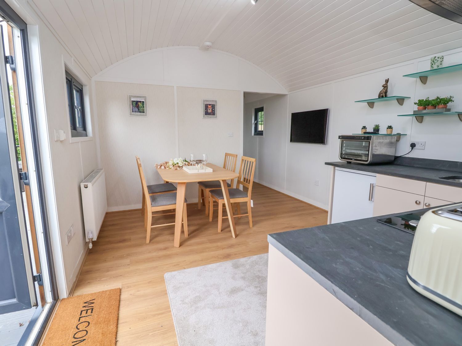 A compact kitchen with a dining area, a built-in oven, and a small TV.