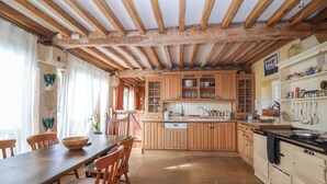 A rustic kitchen with wooden cabinets, a dining table, and chairs. - Highgrove Barn (Stroud)