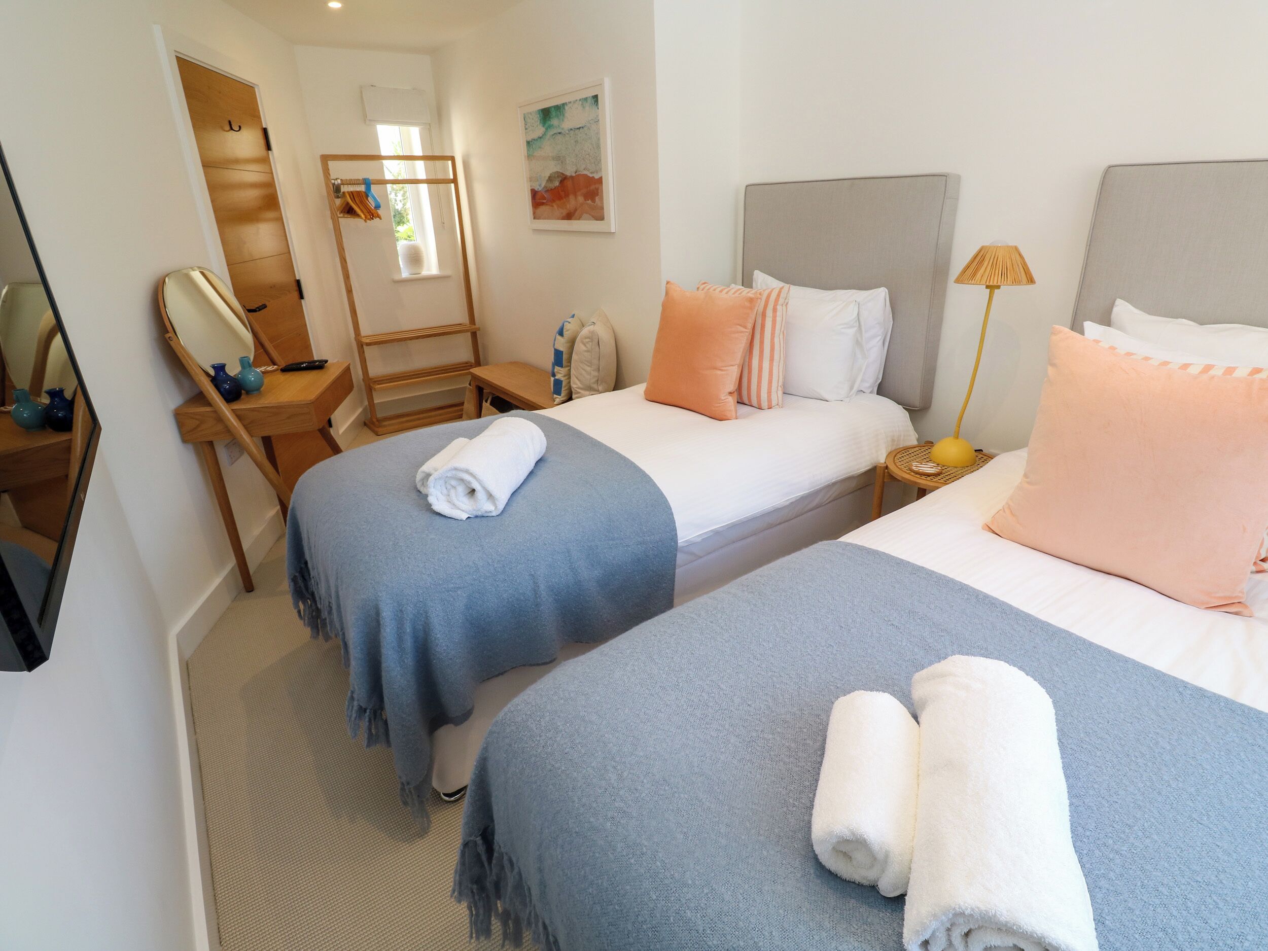 Une chambre d’hôtel avec deux lits, un miroir, une petite table et une lampe.