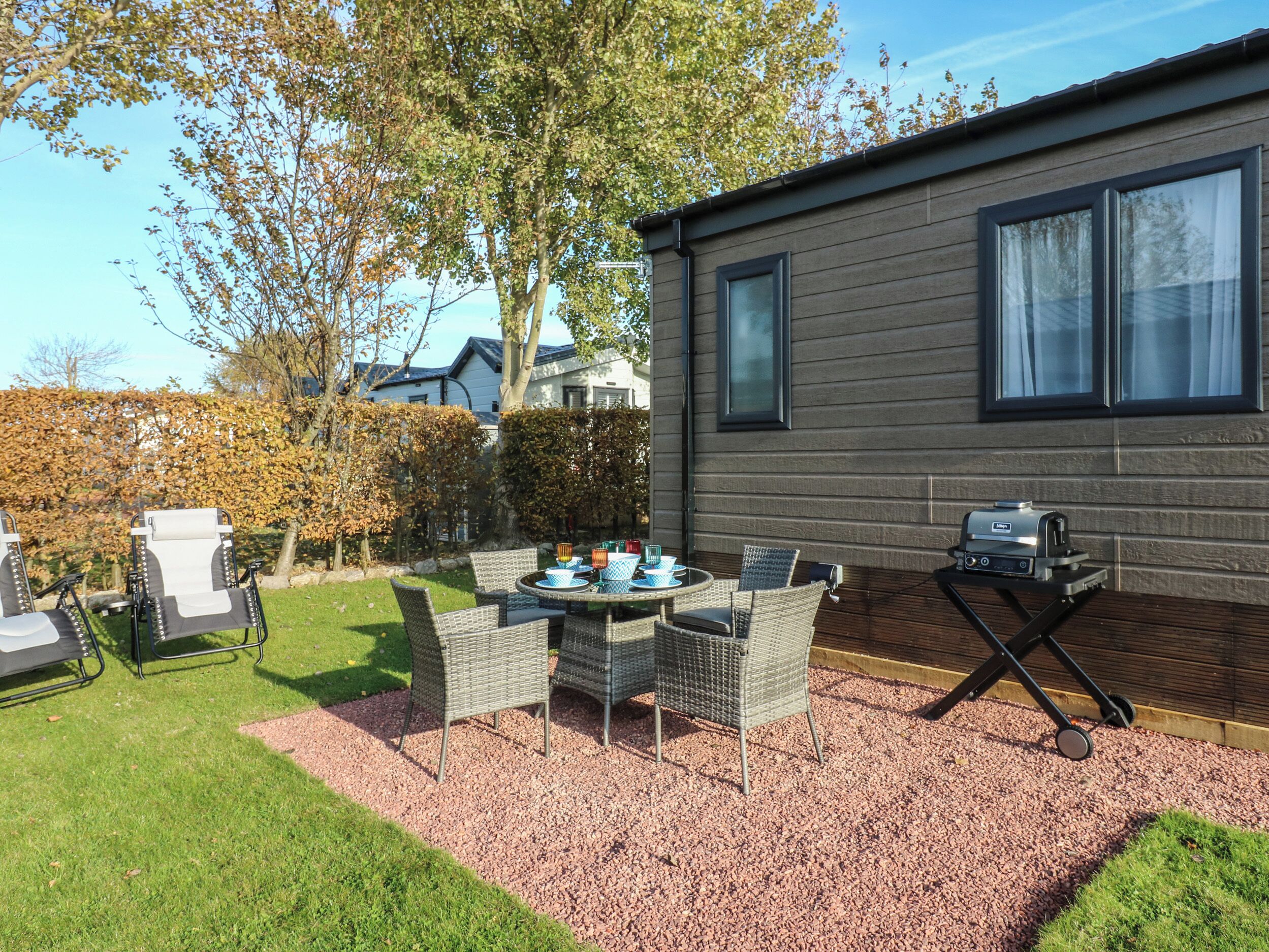 A patio with outdoor furniture, a grill, and a hedge.