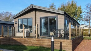 Een modern, gelijkvloers gebouw met grote glasramen en een houten terras.