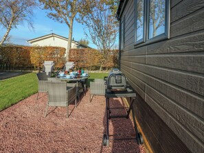 A patio with outdoor furniture, a grill, and a dining table set for a meal. - Brocklebank Lodge, 35 (Carlisle)