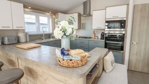 Een moderne keuken met een centraal eiland, inbouwapparatuur en een raam dat voor natuurlijk licht zorgt.