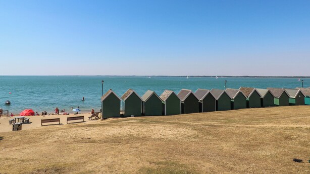 Une plage avec des cabanes de plage vertes et une vue dégagée sur la mer.