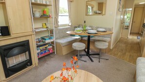 Un espace de vie compact comprenant un coin repas, un canapé, une petite table et une cheminée.