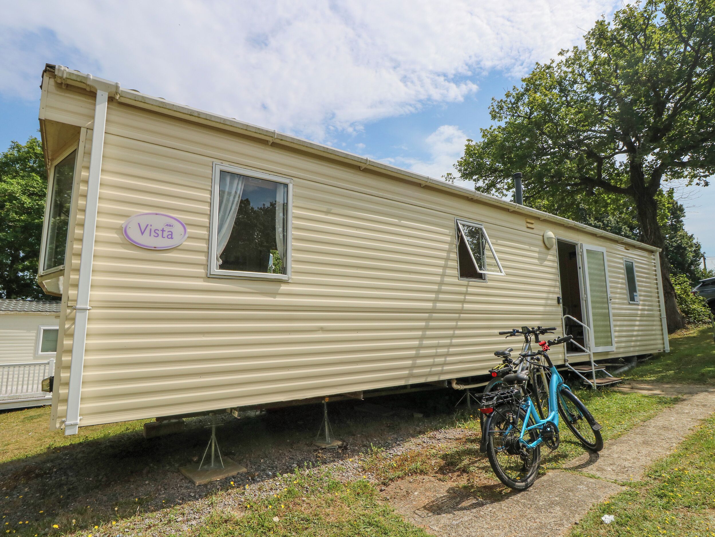 A mobile home with a "Vista" sign, a bicycle, and a small garden area.