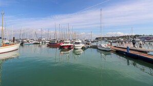 Un port de plaisance où sont amarrés différents types de bateaux, avec une eau calme et un ciel dégagé.