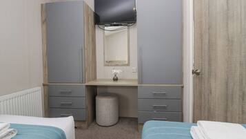 Un dormitorio con dos camas, un aparador, un espejo y un televisor.