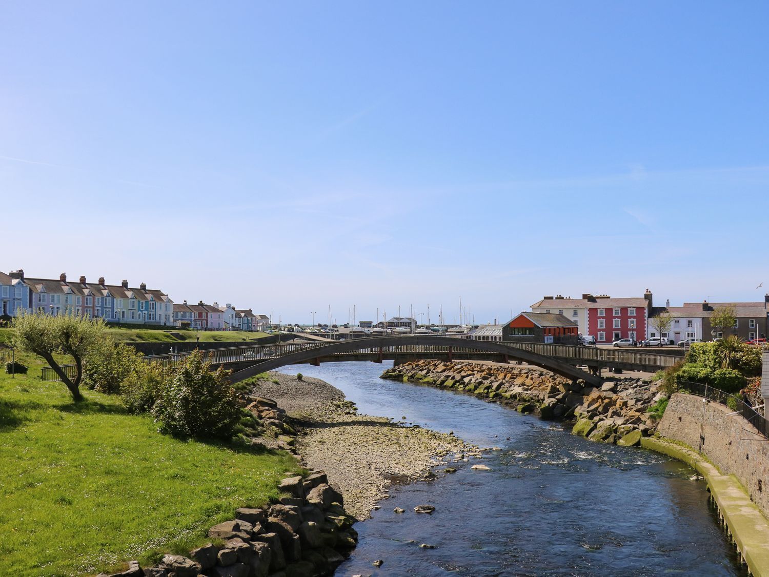 Un río con un puente de piedra, rodeado de edificios residenciales y un puerto deportivo.