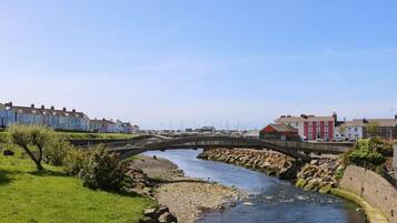 Un río con un puente de piedra, rodeado de edificios residenciales y un puerto deportivo.