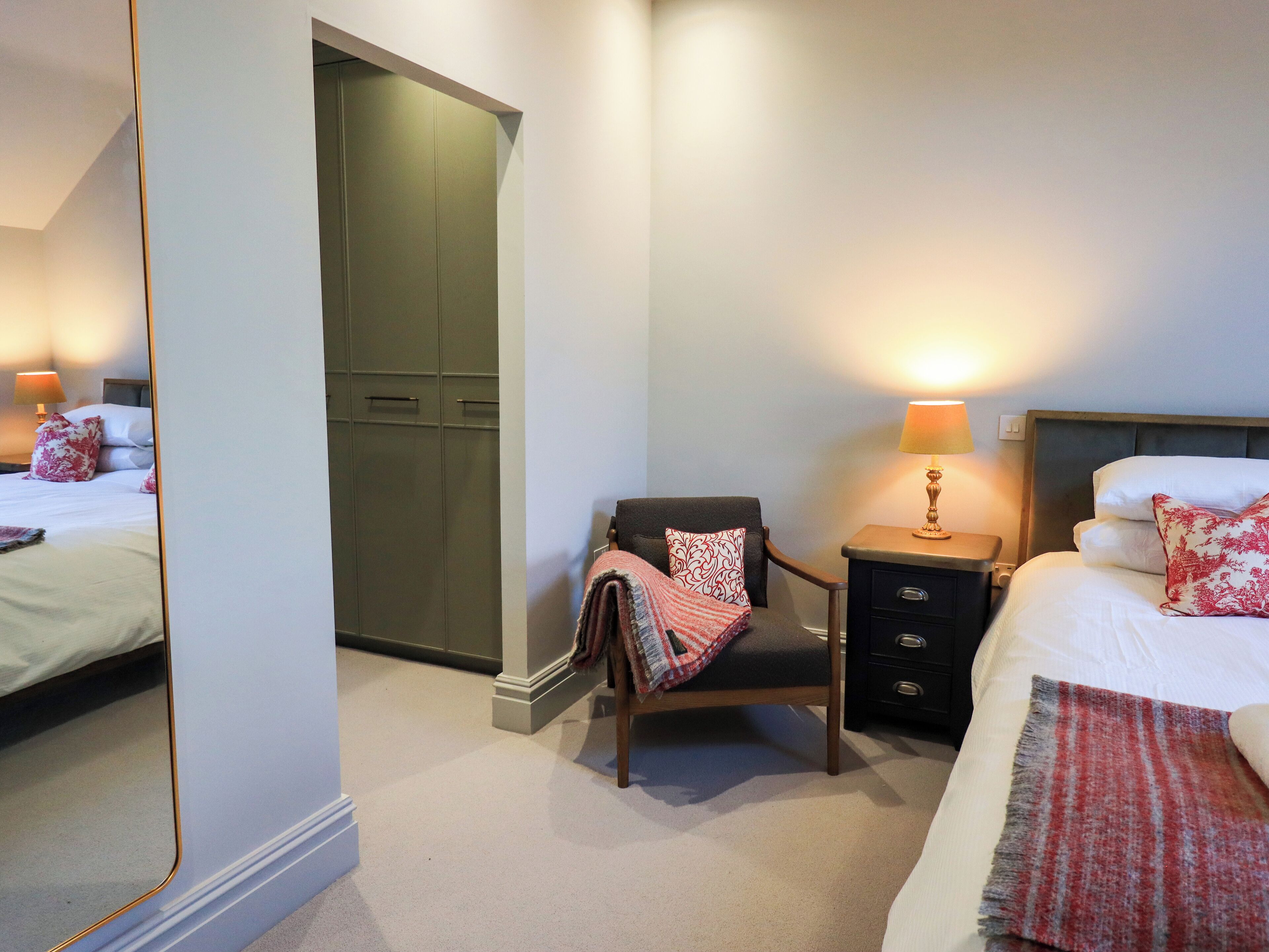 A hotel room with a bed, a chair, a nightstand, and a wardrobe.