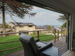 A balcony with wicker furniture, a view of houses, and a grassy area. - The Bay (Tyn-y-Gongl)