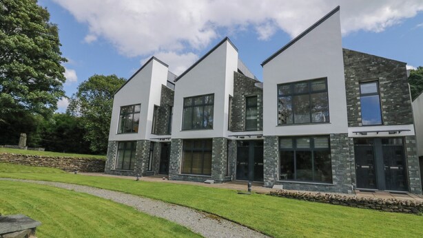 A modern multi-story house with large windows and stone accents. - 12 Blue Hill Park (Ambleside)