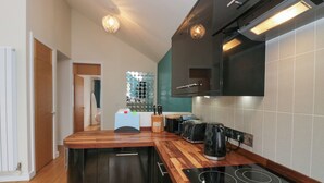 A modern kitchen with wooden countertops, a built-in stove, and a backsplash of circular mirrors. - 12 Blue Hill Park (Ambleside)
