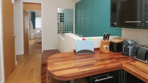 A modern kitchen with wooden countertops, a built-in oven, and a teal accent wall. - 12 Blue Hill Park (Ambleside)