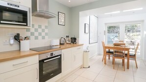 A modern kitchen with a microwave, oven, and gas stove, a dining area with a table and chairs, and a view of the outdoors through a glass door.