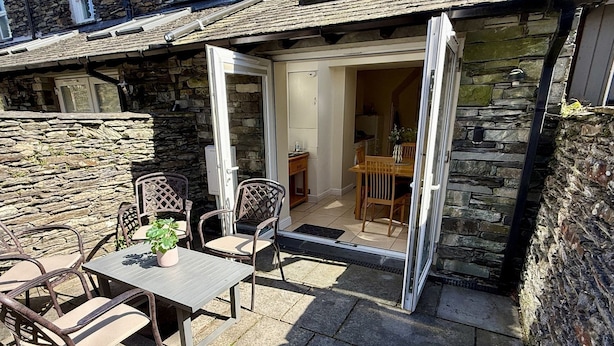 A stone house with an open door leading to a dining area with a table and chairs.