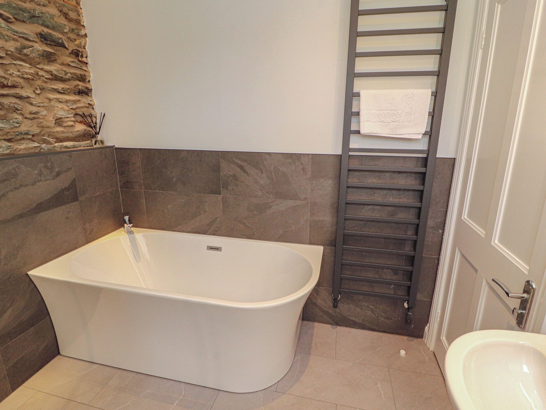 A modern bathroom with a freestanding bathtub, a towel rack, and a toilet.