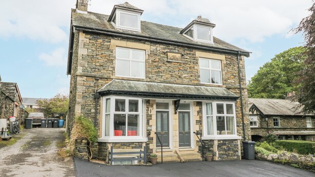 A stone house with a bay window, a front door, and a small porch area. - Park Beck 3 (Windermere)