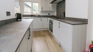 A modern kitchen with white cabinetry, a built-in oven, and a large window providing natural light. - Park Beck 3 (Windermere)
