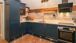 Une cuisine moderne avec des meubles de couleur bleu foncé, un four encastré et un four à micro-ondes.