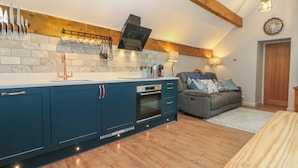 Une cuisine moderne dotée d’un grand îlot central, de poutres en bois et d’un coin salon confortable avec un canapé et un ours en peluche.