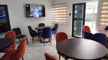 A conference room with a TV mounted on the wall, a round table, and chairs with a mix of red and blue upholstery.