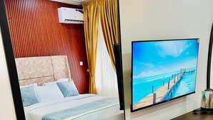 Una habitación de hotel con cama, televisión, escritorio y una mesita.