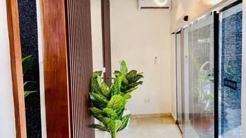A hallway with a wooden slatted wall, a potted plant, and a glass door leading outside.