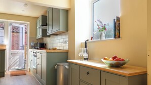 A compact kitchen with a window, a sink, and a fruit bowl on the counter. - 30 Fleet Street (Beaminster)