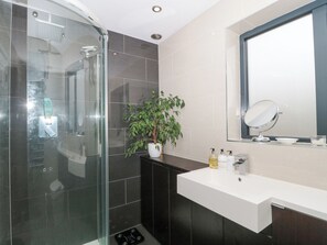 A modern bathroom with a glass shower enclosure, a white sink, and a mirror above it. - Orchard Leigh (Bridgwater)
