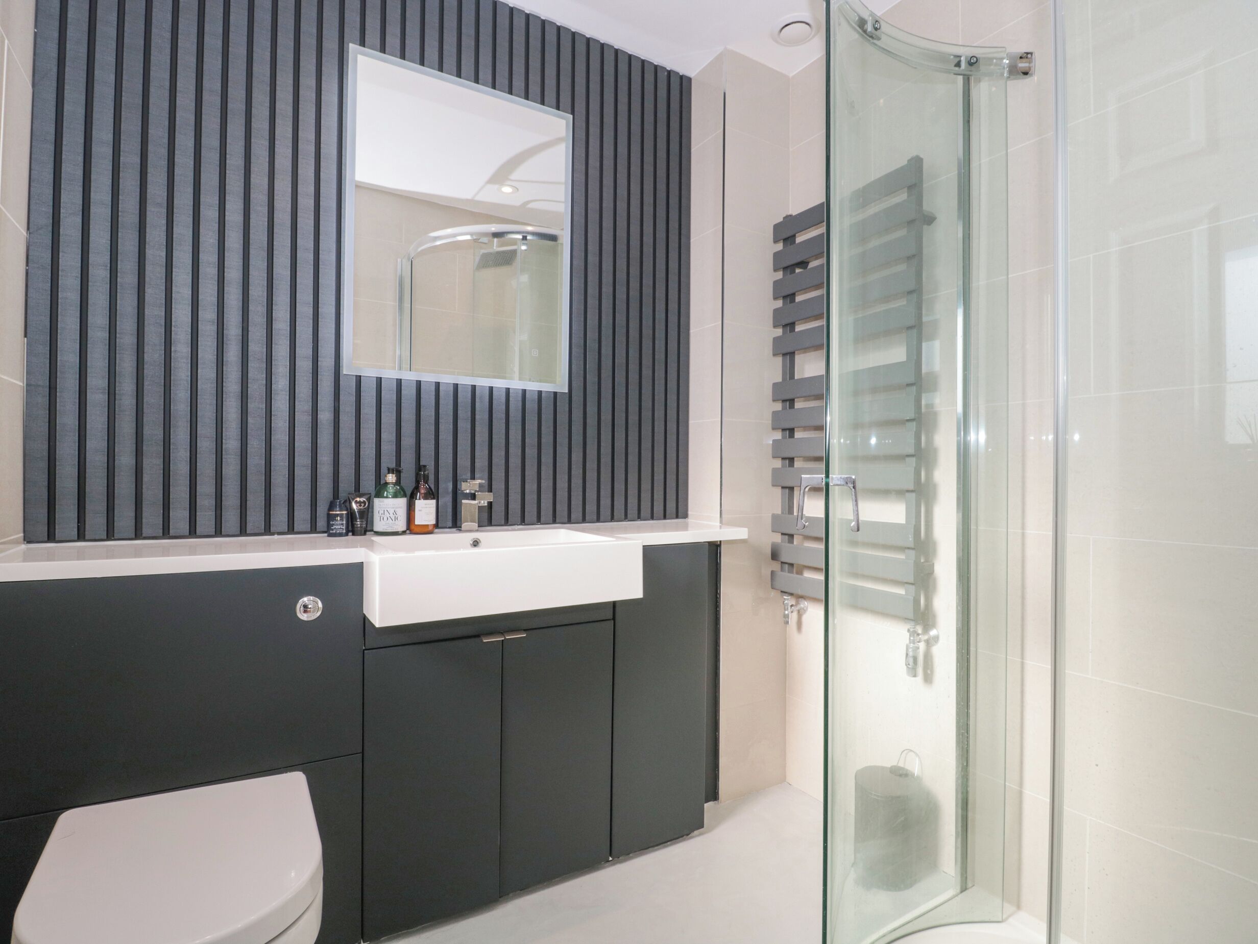 Une salle de bain moderne avec une douche à parois de verre, un meuble-lavabo avec un miroir et des toilettes.