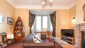 Ein Wohnzimmer mit braunem Sofa, einer Holzregalanlage, einem Fernseher und einem Kamin.