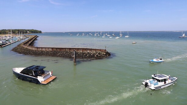 A marina with several boats docked, a wooden breakwater, and a clear blue sky. - Whitfield P10 (Yarmouth)