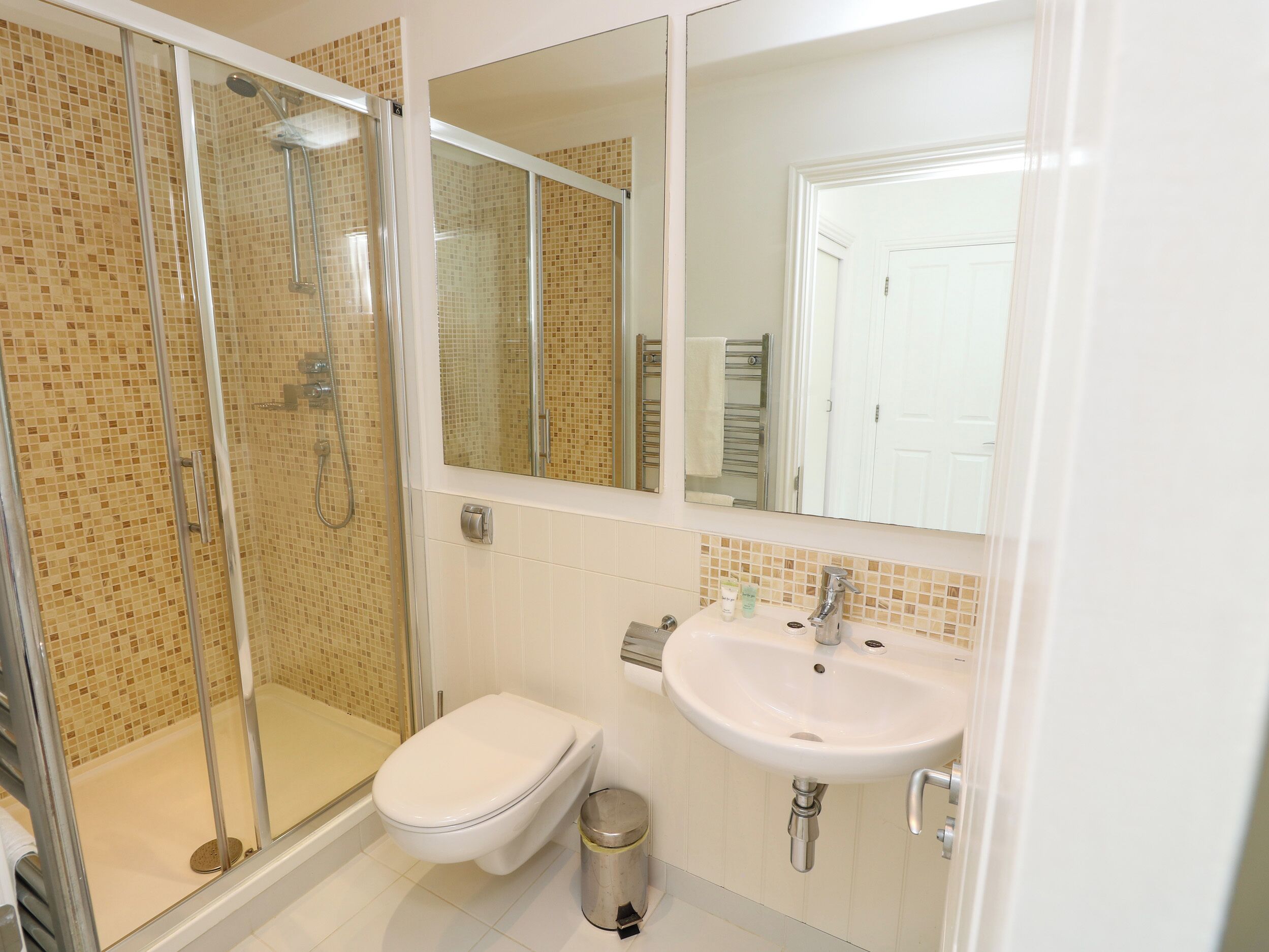 Une salle de bain avec une douche à parois de verre, des toilettes, un lavabo et un miroir.