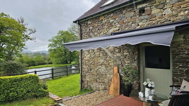 A stone building with a wooden deck and outdoor seating area. - The Old Workshop (Llanybydder)