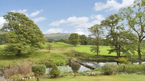 A serene landscape with a pond, lush greenery, and trees. - Riverbank At Stepping Stones (Ambleside)