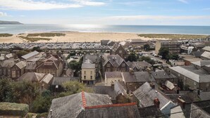 A coastal town with a beach, parked cars, and historic buildings. - Tonnau Yr Oleu or Waves of Light (Barmouth)