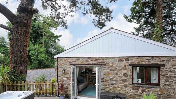 A stone building with a glass door leading to a patio area. - Tarka View (Bideford)