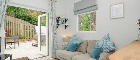 Un accogliente soggiorno con divano, tavolo da pranzo e vista su un giardino tramite una porta-finestra.