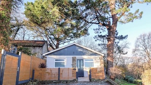A small, single-story house with a stone foundation and a wooden fence. - Tarka View (Bideford)
