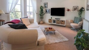 Un salon avec un canapé, une table basse, un téléviseur et une plante.