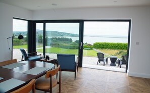 Comedor con mesa y sillas, ventanas amplias con vista a un campo de golf y una masa de agua.